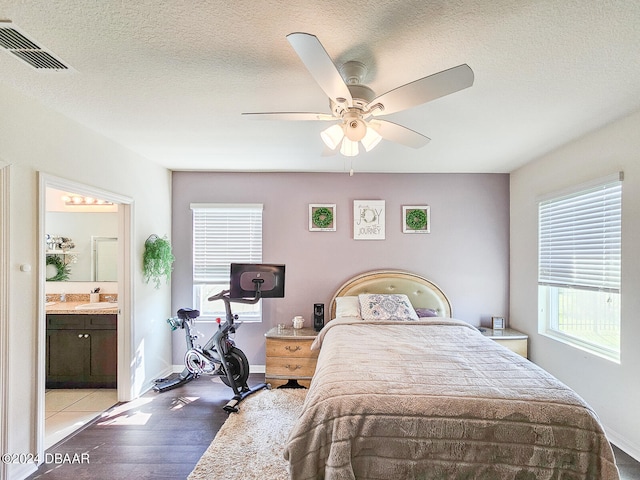 bedroom featuring connected bathroom, light wood-type flooring, a textured ceiling, sink, and ceiling fan