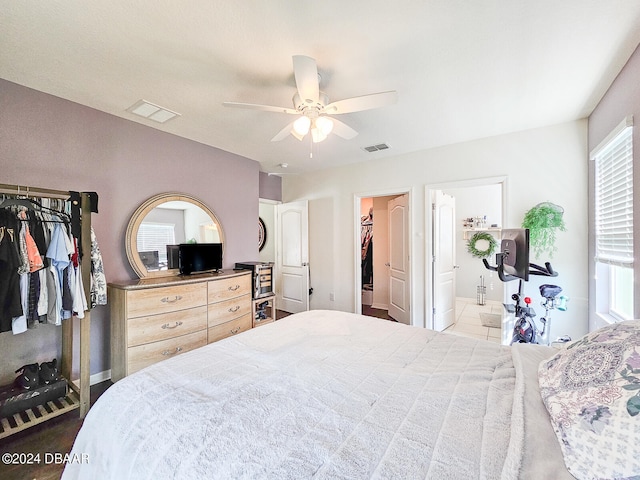 bedroom featuring a closet, a spacious closet, ceiling fan, and ensuite bath