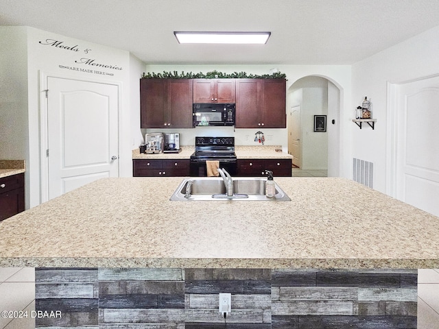 kitchen with a kitchen island with sink, black appliances, and sink