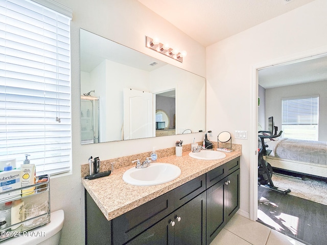 bathroom featuring toilet, vanity, tile patterned flooring, and a shower with shower door