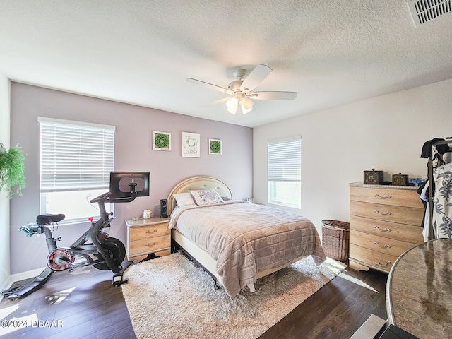 bedroom with dark wood-type flooring, ceiling fan, and a textured ceiling