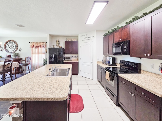 kitchen with sink, black appliances, a textured ceiling, light tile patterned floors, and an island with sink