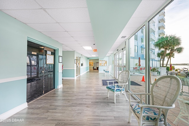 corridor featuring wood-type flooring and a drop ceiling