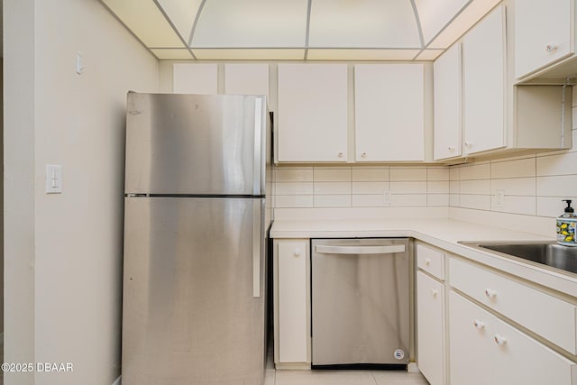 kitchen with backsplash, light tile patterned flooring, white cabinets, and stainless steel appliances