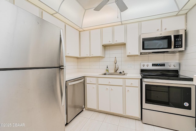 kitchen featuring ceiling fan, sink, stainless steel appliances, light tile patterned floors, and white cabinets