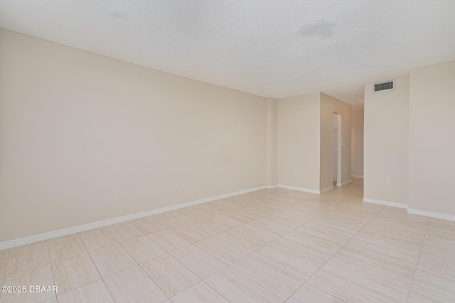 empty room with light tile patterned flooring and a textured ceiling