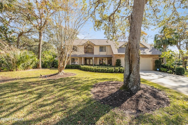 view of front of house featuring a front yard, concrete driveway, brick siding, and an attached garage