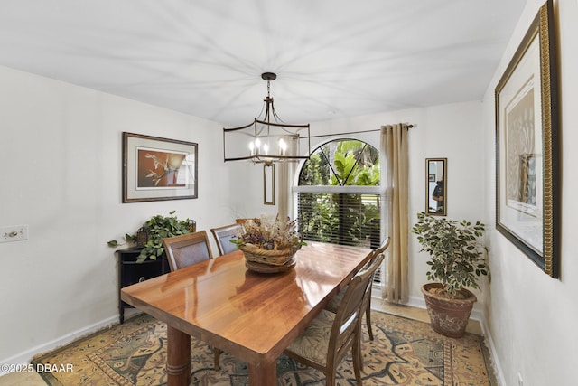 dining area with a chandelier, light tile patterned floors, and baseboards