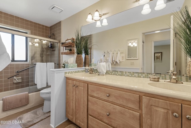 full bath featuring double vanity, combined bath / shower with glass door, a sink, and toilet