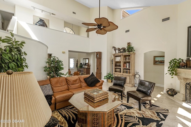 living area with ceiling fan, a fireplace, arched walkways, and visible vents