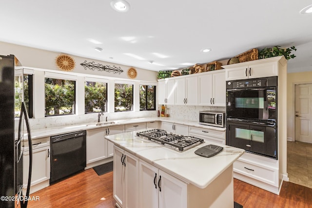 kitchen featuring black appliances, a sink, white cabinetry, and light wood-style floors