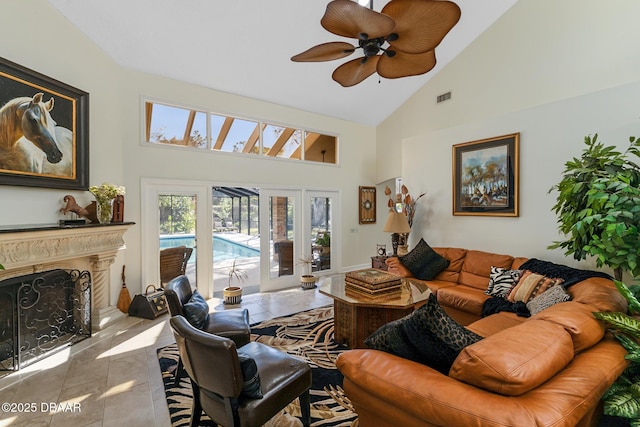 living area with a ceiling fan, a high end fireplace, visible vents, and high vaulted ceiling