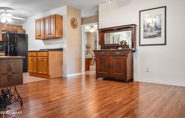 2835 Nordman Ave, New Smyrna Beach, FL 32168 - kitchen featuring a ceiling fan, black refrigerator with ice dispenser, light wood-type flooring, baseboards, and brown cabinetry