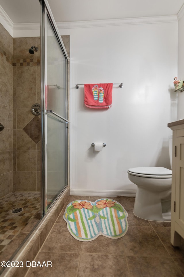 bathroom featuring tile patterned floors, toilet, ornamental molding, and a shower with door