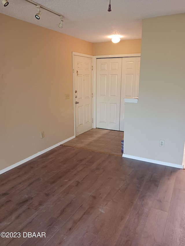 spare room featuring dark wood-type flooring and a textured ceiling