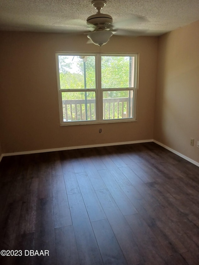 empty room featuring ceiling fan, dark hardwood / wood-style floors, plenty of natural light, and a textured ceiling