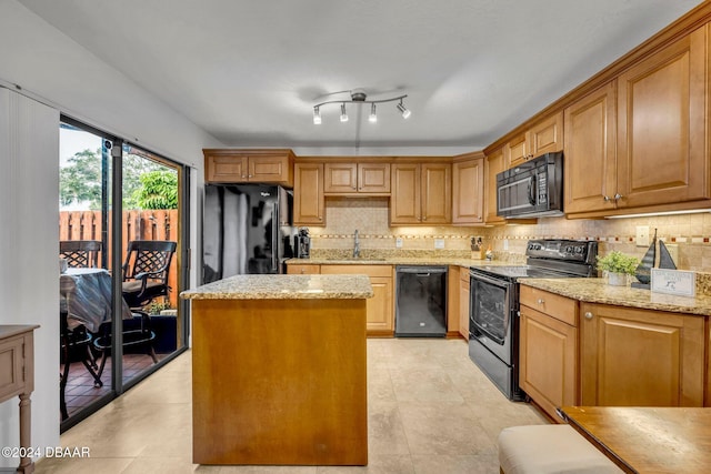 kitchen with sink, a center island, tasteful backsplash, light stone countertops, and black appliances