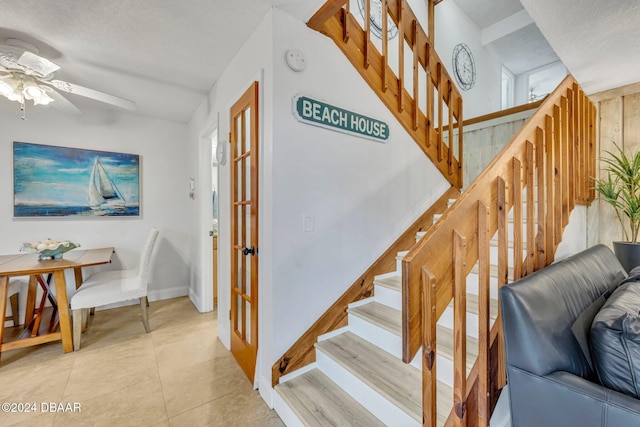 staircase with a textured ceiling, tile patterned floors, and ceiling fan