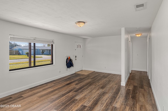 empty room featuring wood finished floors, visible vents, and baseboards