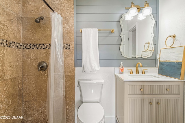 bathroom with toilet, a tile shower, and vanity