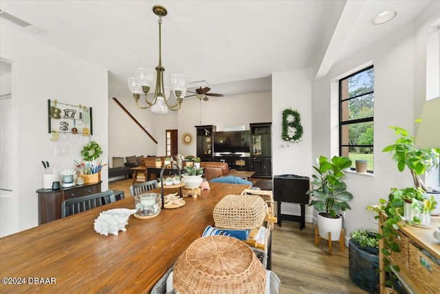 dining area with ceiling fan with notable chandelier and hardwood / wood-style flooring