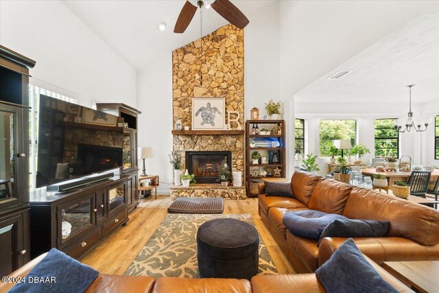 living room with high vaulted ceiling, light wood-type flooring, ceiling fan with notable chandelier, and a fireplace