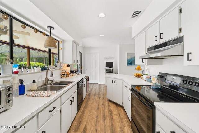 kitchen with white cabinets, light hardwood / wood-style floors, black appliances, and decorative light fixtures