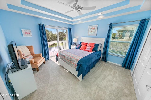 carpeted bedroom featuring ceiling fan, a closet, access to outside, and a tray ceiling