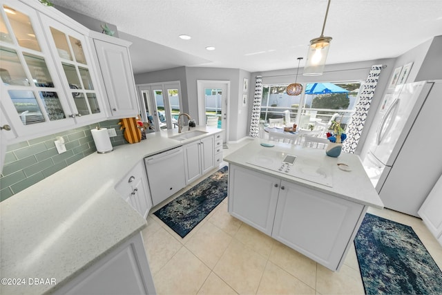 kitchen with sink, pendant lighting, white appliances, decorative backsplash, and white cabinets