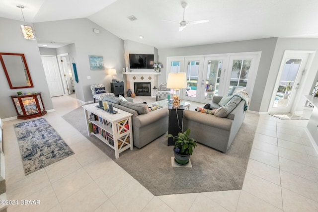 living room with french doors, ceiling fan, a tile fireplace, light tile patterned floors, and lofted ceiling