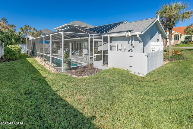 back of house featuring glass enclosure, a fenced in pool, and a yard