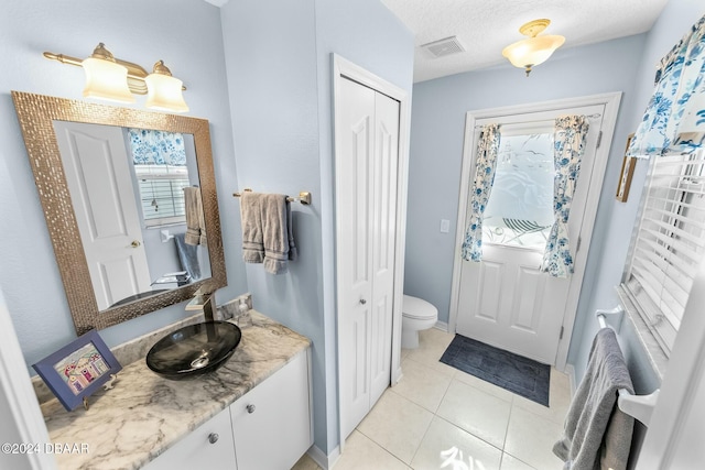 bathroom featuring tile patterned flooring, a textured ceiling, vanity, and toilet