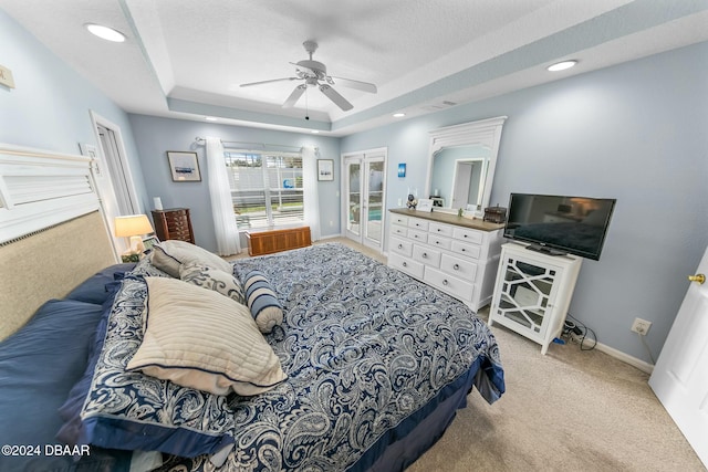 carpeted bedroom featuring a raised ceiling, ceiling fan, and a textured ceiling