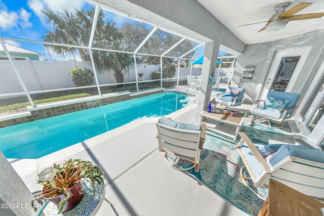 view of swimming pool with glass enclosure, ceiling fan, and a patio area