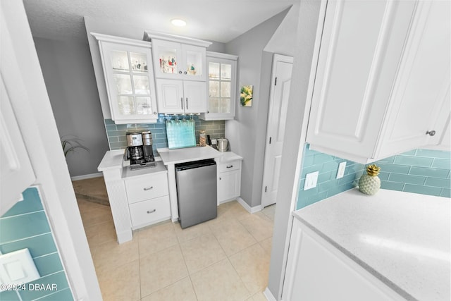 kitchen featuring tasteful backsplash, stainless steel refrigerator, and white cabinetry