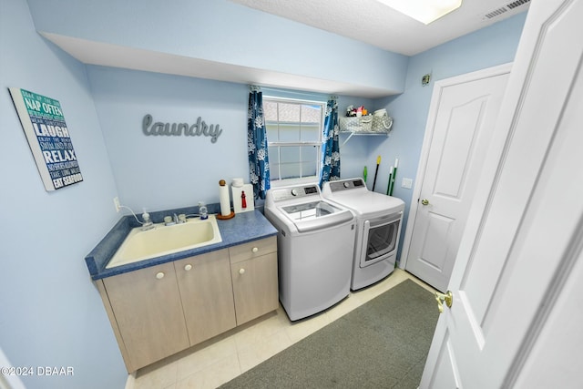 clothes washing area with sink, cabinets, independent washer and dryer, a textured ceiling, and light tile patterned floors