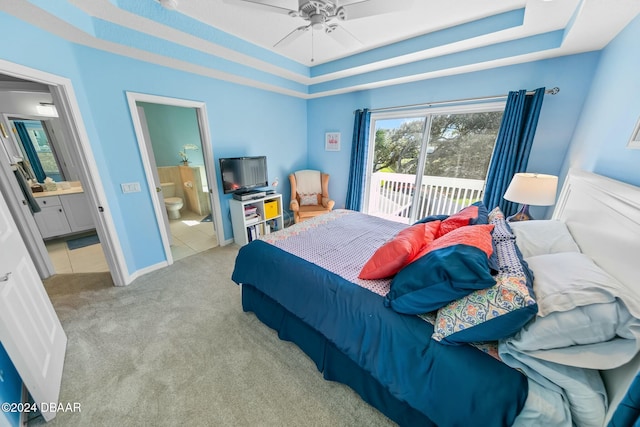 carpeted bedroom featuring access to exterior, ensuite bathroom, a raised ceiling, and ceiling fan