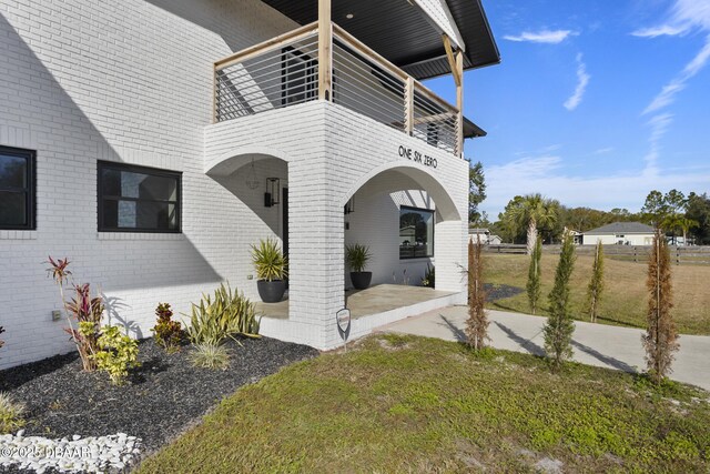 view of front of property featuring a balcony, a front lawn, a garage, and an outbuilding