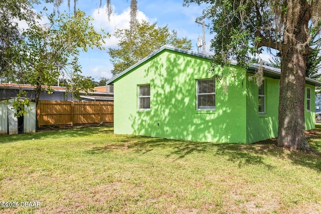 view of property exterior with a yard, fence, and stucco siding