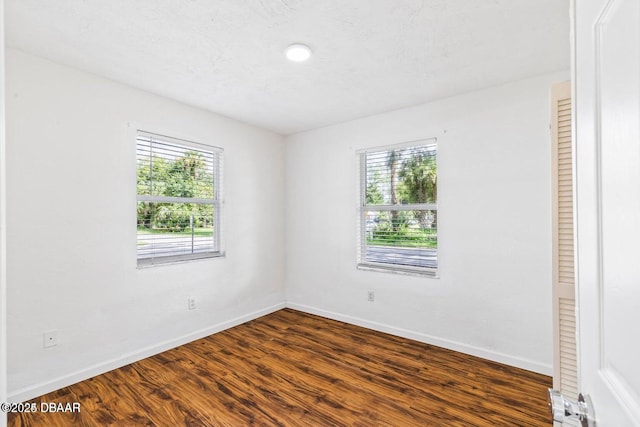 unfurnished room featuring dark wood-type flooring and baseboards