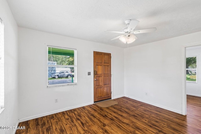 empty room featuring baseboards, a healthy amount of sunlight, and dark wood-style floors