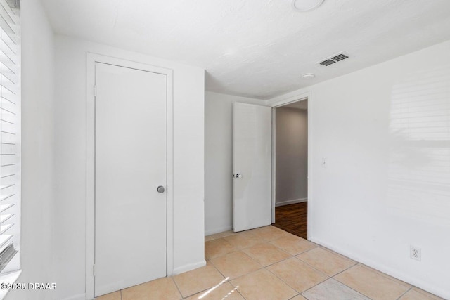 unfurnished bedroom featuring visible vents, a closet, and light tile patterned flooring