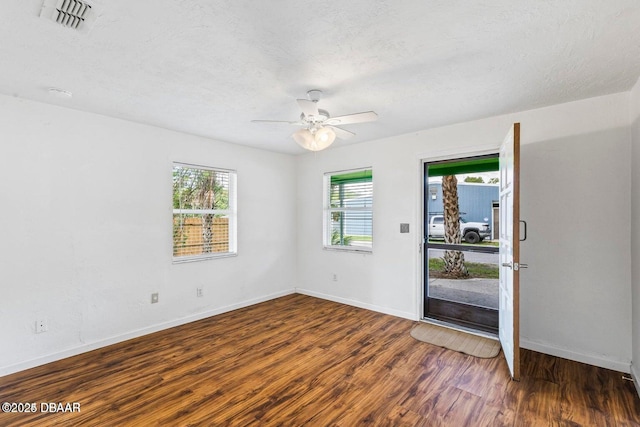 unfurnished room featuring visible vents, a textured ceiling, baseboards, and wood finished floors