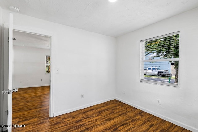 empty room featuring wood finished floors, baseboards, and a textured ceiling