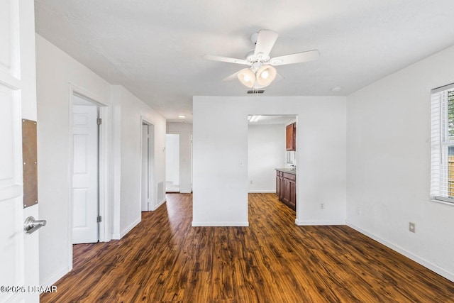 unfurnished room with visible vents, baseboards, ceiling fan, and dark wood-style flooring