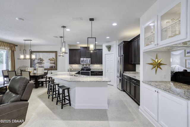 47 Abacus Ave, Ormond Beach, FL 32174 - kitchen with stainless steel appliances, open floor plan, a sink, light stone counters, and glass insert cabinets