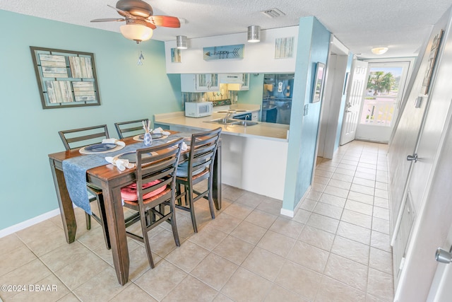 dining space with ceiling fan, light tile patterned floors, and a textured ceiling