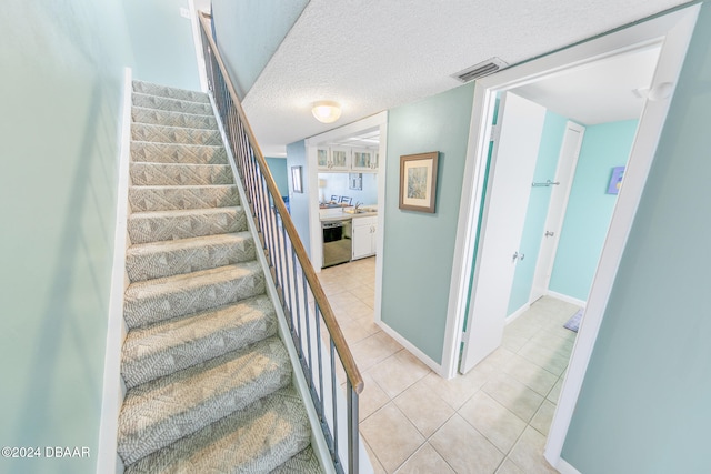 staircase with tile patterned floors, sink, and a textured ceiling