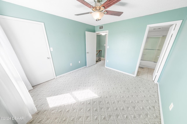 unfurnished bedroom with ceiling fan, light colored carpet, and connected bathroom