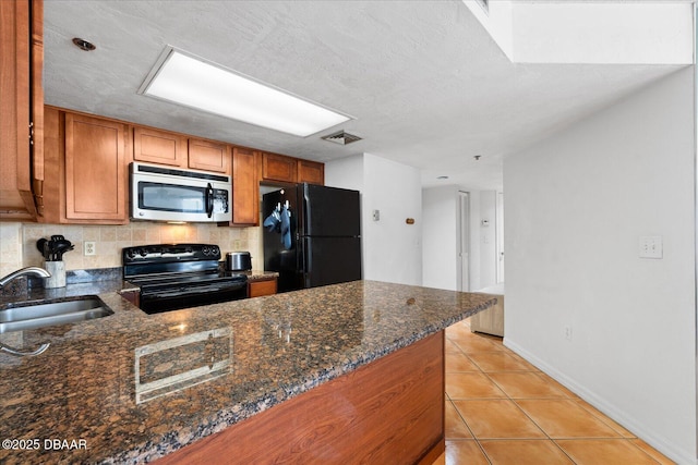 kitchen with a sink, light tile patterned floors, brown cabinetry, black appliances, and visible vents